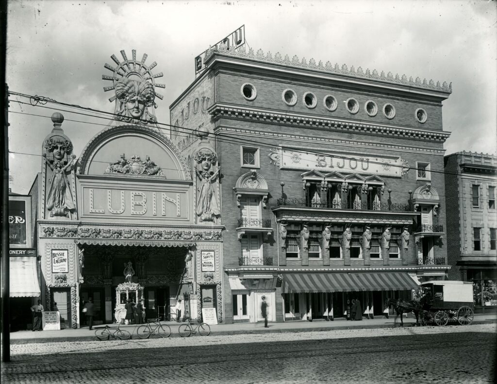 Exterior of Lubin and Bijou Theaters. The Lubin has bicycles out front and the Bijoy has a horse and cart out front. 