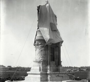 A group of people around the Lee Monument that is covered by a veil.