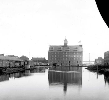 The turning basin in Richmond’s canal bordered by the five-story Gallego Flour Mills building, a railroad cars, and other industrial buildings.