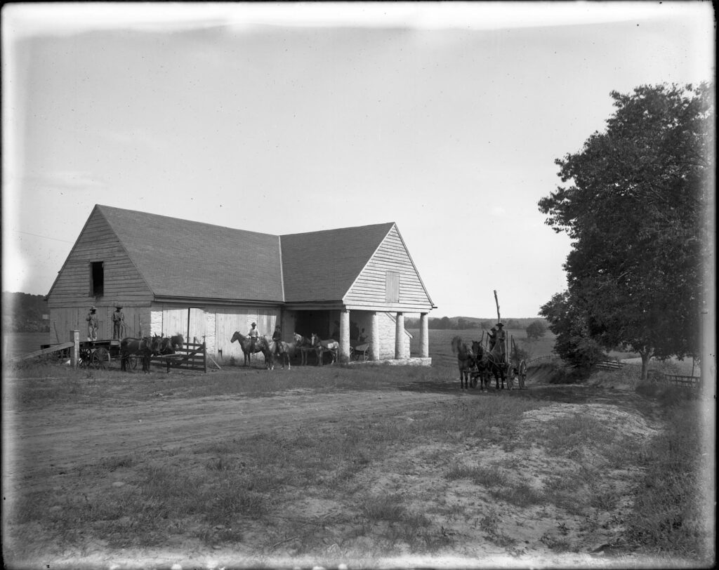 A horse barn at St. Emma Industrial & Agricultural Institute at Belmead Plantation, Powhatan County, near Richmond; image of several young men on horseback with others driving wagons.