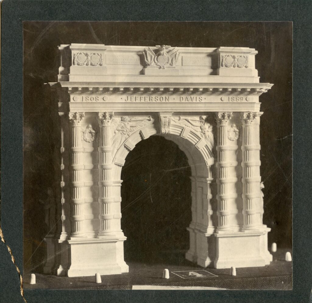 Image of the Jefferson Davis Memorial arch. Large white arch with two columns on either side with Jefferson Davis’ name in the middle above the arch.